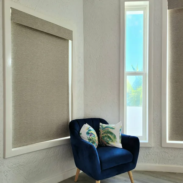 Roller shade over a window beside a navy armchair